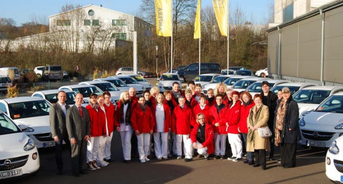 Karin Decker, stellvertretendes Vorstandsmitglied der Stadtsparkasse Kaiserslautern, Vertreterinnen der Sozialstation mit vielen Mitarbeiter/-innen und Geschäftsführer des Autohauses Hübner bei der Übergabe der 25 Opel ADAM.